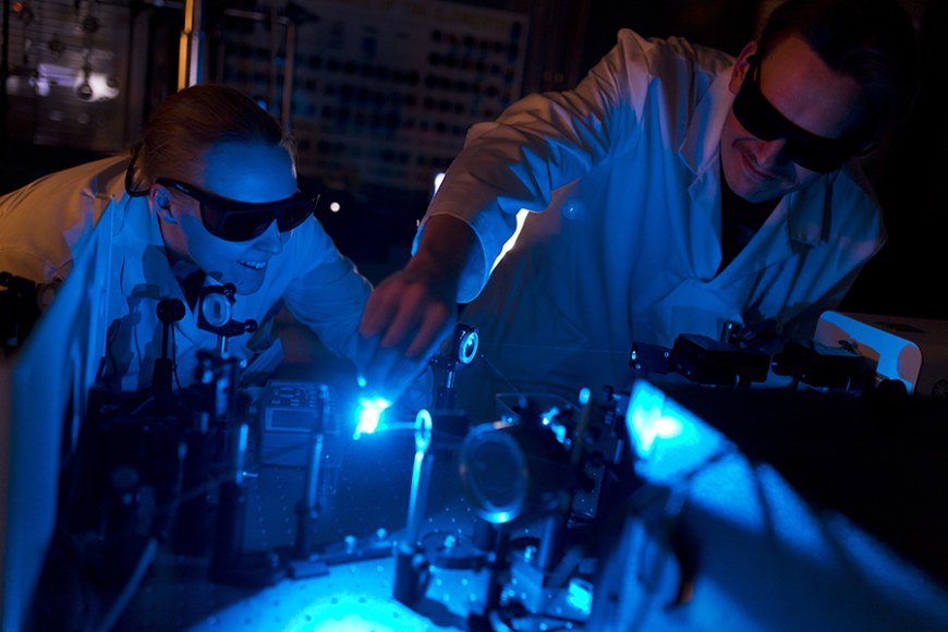 nainen ja mies suojalasit silmillä tutkivat valoa laboratoriolaitteilla
