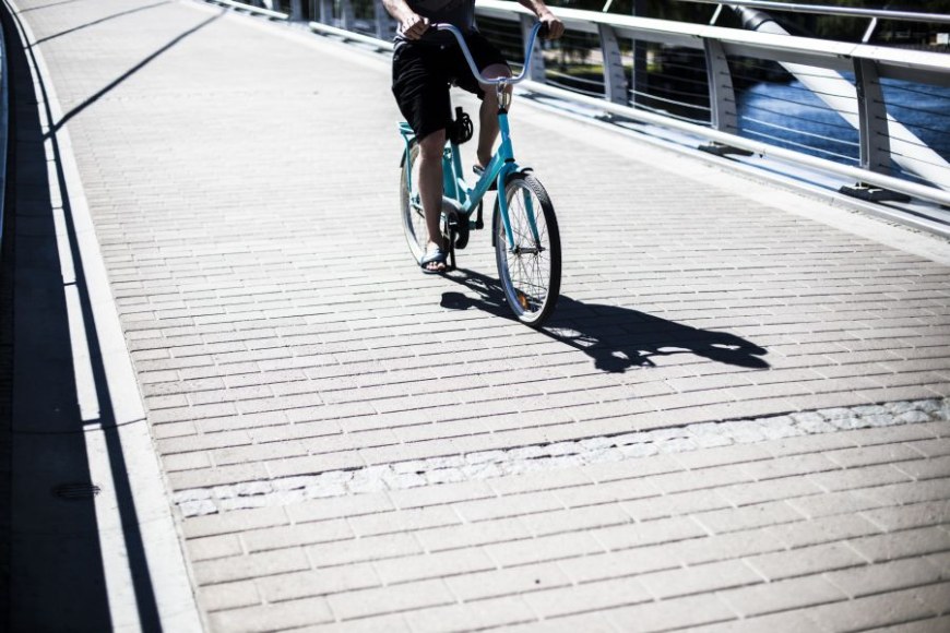 tunnistamaton ihminen ajaa polkupyörällä siltaa pitkin
