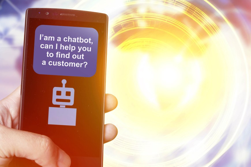 Käsi pitelee matkapuhelinta, jossa keskustelu chatbotin kanssa alkamassa. 