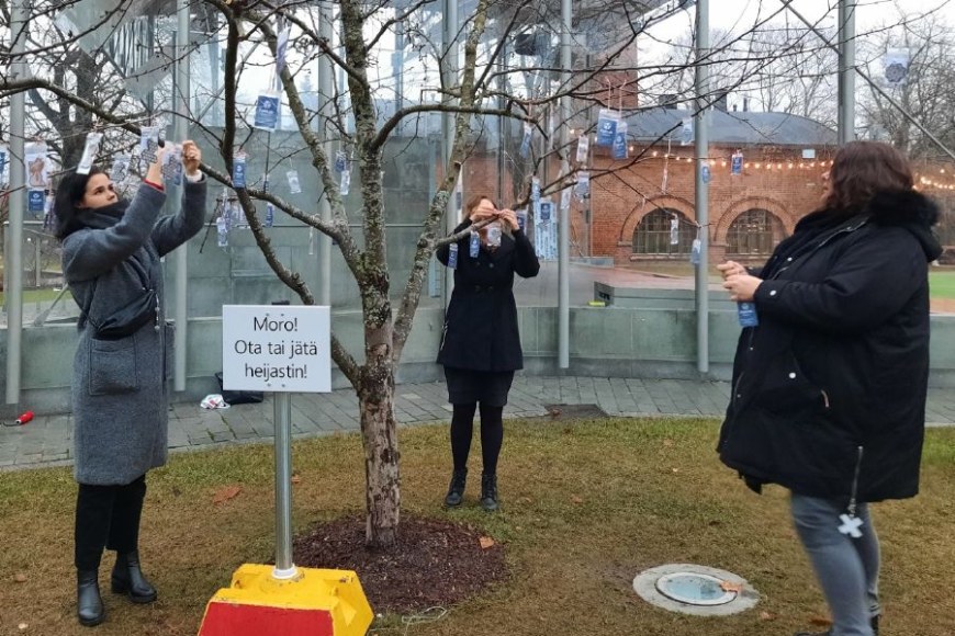 Taru Arvio, Noora Nyberg ja Hanne Lehtola ripustavat heijastimia heijastinpuuhun.