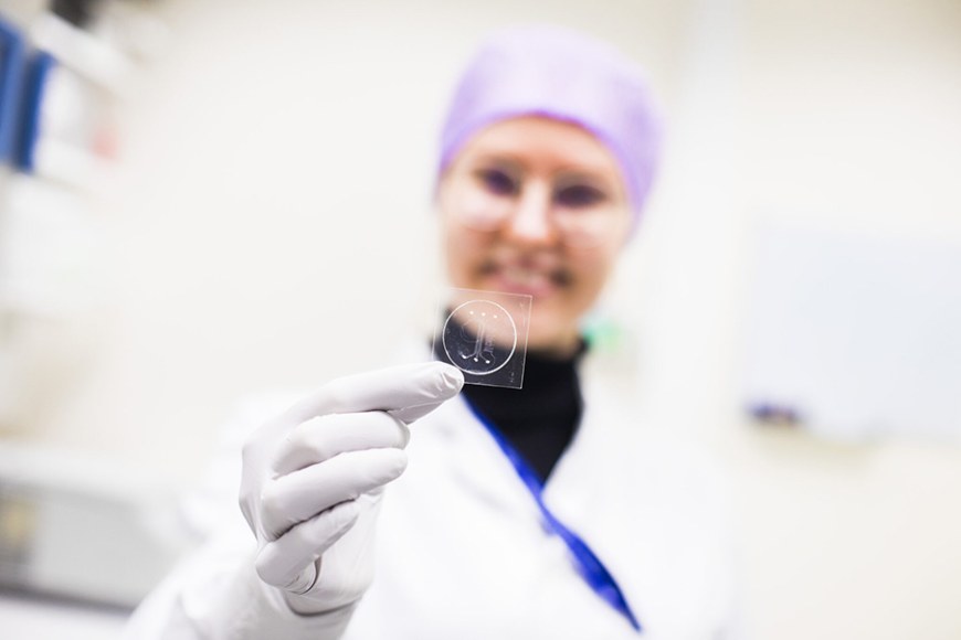 Tutkija Hanna Vuorenpäällä on kädessään chip-monikudosmallialusta. Monikudosmallinnuksessa yhdistetään kantasolutekniikkaa ja mikroteknologiaa ihmiskehon toimintoja jäljittelevän monikudosmallin kehittämiseksi.