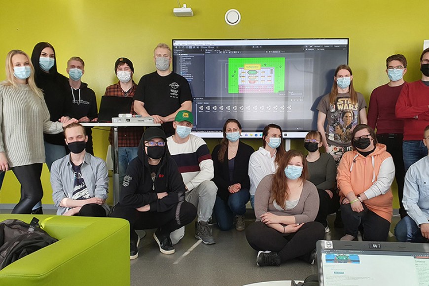 Iloisia tietojenkäsittelyn opiskelijoita luokassa maskit kasvoilla.