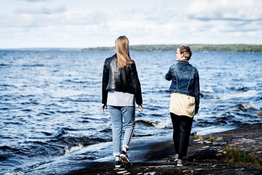 Kaksi nuorta kävelemässä poispäin järvenrannalla Tampereella.