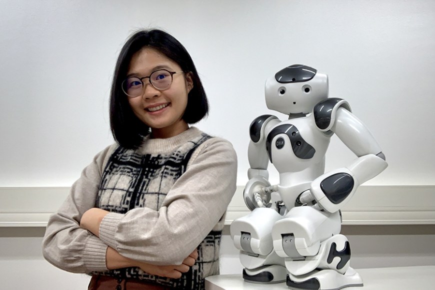A person poses with a robot