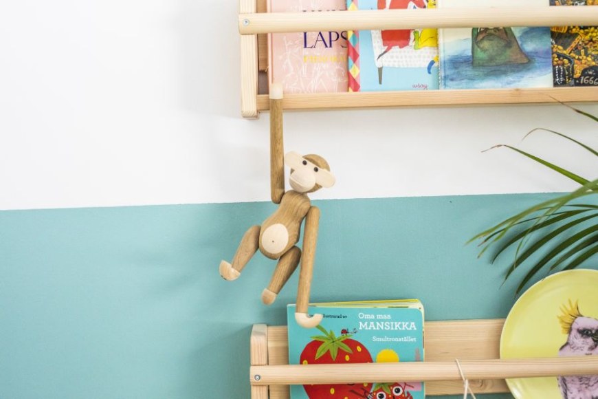 Lastenkirjoja hyllyssä, josta roikkuu leluapina.