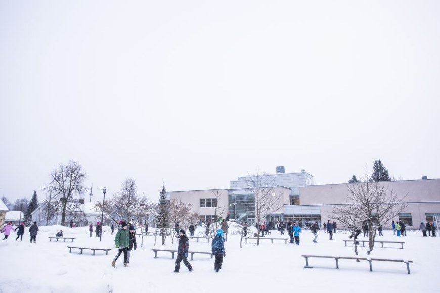 Tampereen yliopiston normaalikoulu kuvattuna talvella. Koulun pihalla runsaasti lapsia. 