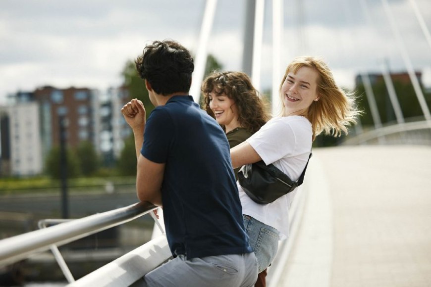 Kolme iloista nuorta nojailee sillan kaiteeseen Tampereella.