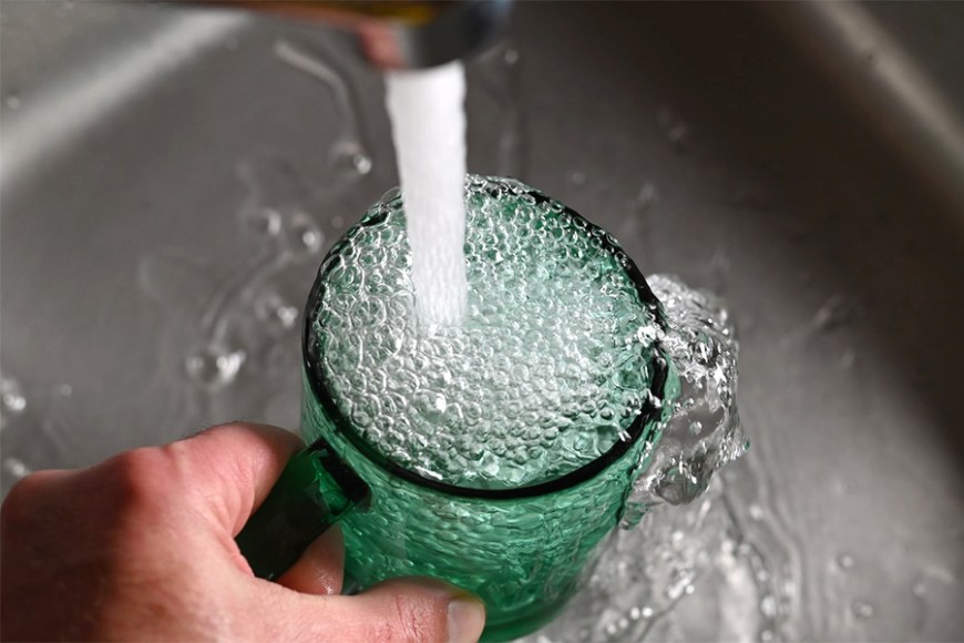 Hanasta valutetaan vettä vihreään juomalasiin.