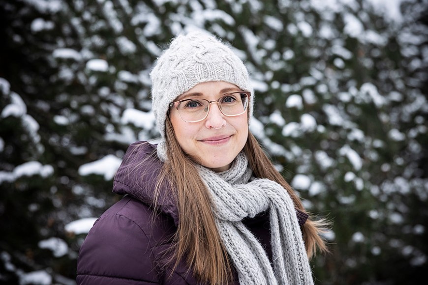 Puolivartalokuva Anja Kärjestä, jolla on yllään vaalea myssy ja kaulahuivi sekä violetti toppatakki. Taustalla näkyy lumisia kuusia.