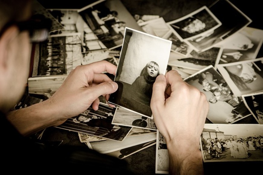 Mustavalkoisia valokuvia pöydällä ja henkilön kädessä