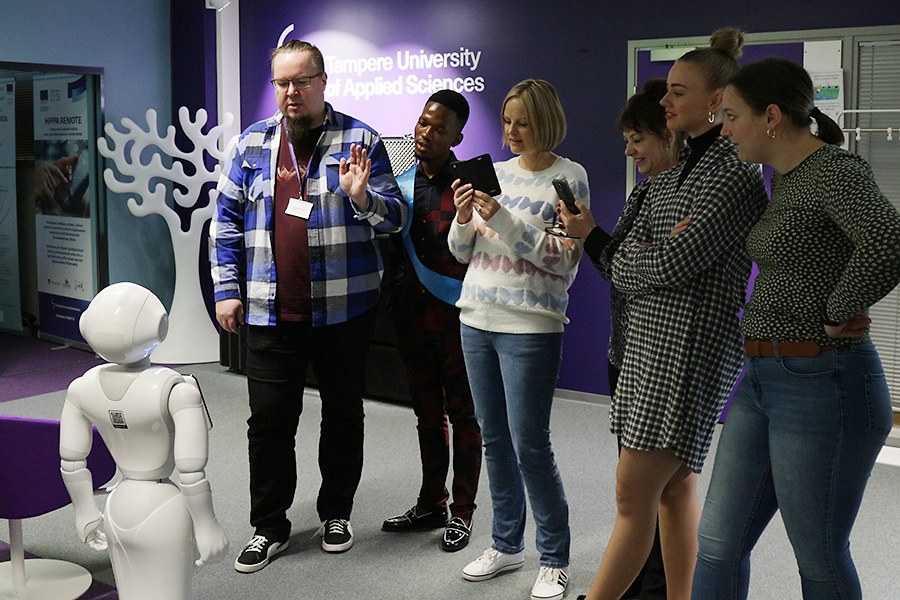 Eteläafrikkalaisia ja suomalaisia opiskelijoita ja opettajia tutustumassa Sote Virtual Labin robottiin. 