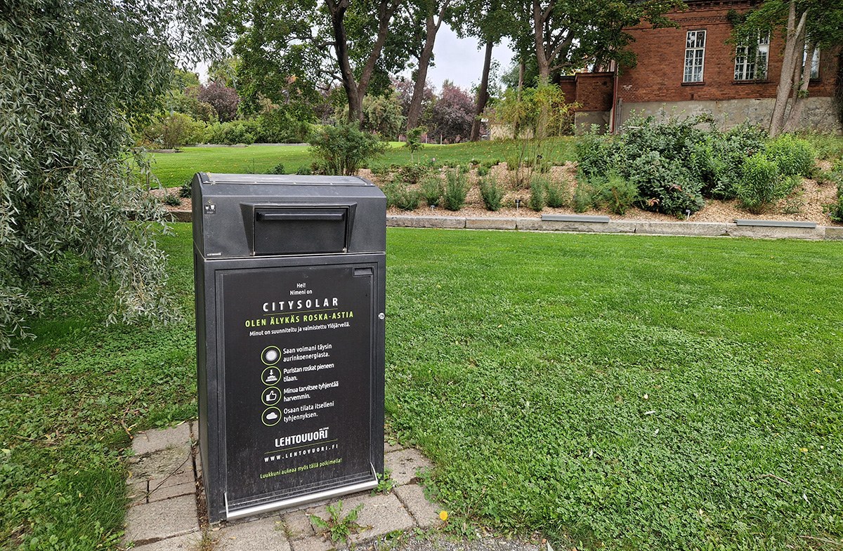 A smart trash bin in a green park. 