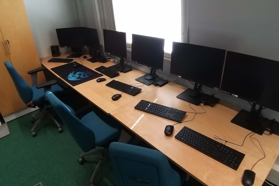 computer displays on desks with chairs in front.