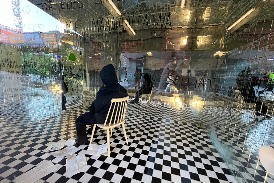 Ikkunagalleriassa taideteos, jossa ihmistä muistuttava hahmo istuu tuolilla