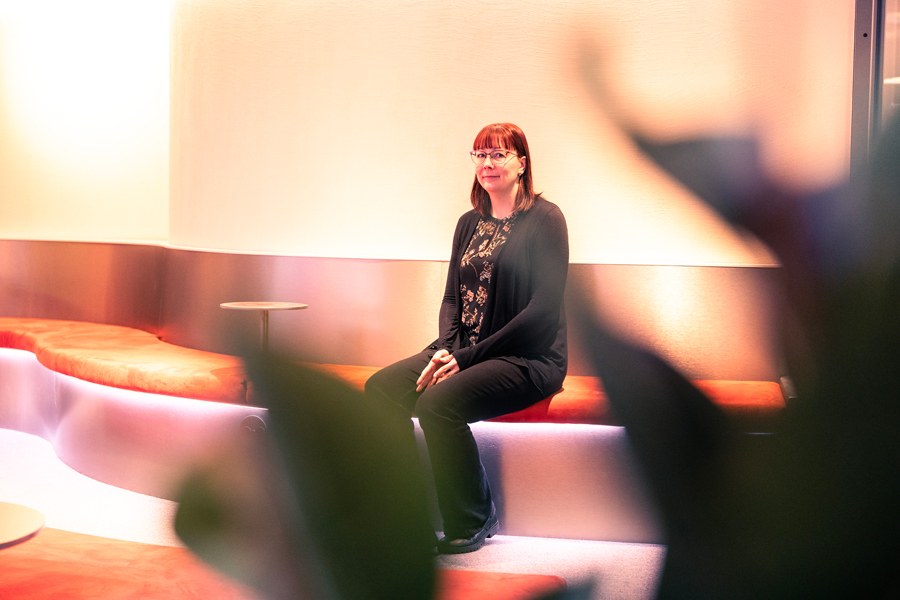 Punahiuksinen nainen istuu sohvalla ja katsoo kameraan.