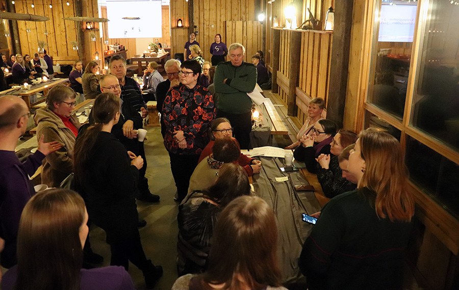 Ihmisiä kokoontuneena keskustelemaan kylätalossa.