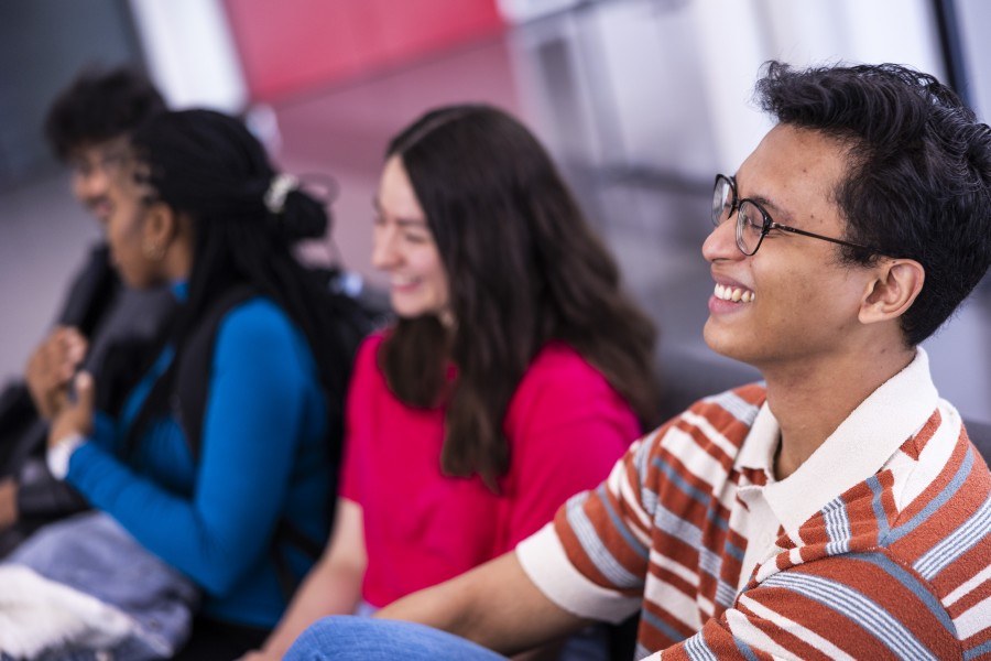 Neljä opiskelijaa istuu sohvalla katsoen pois kamerasta.