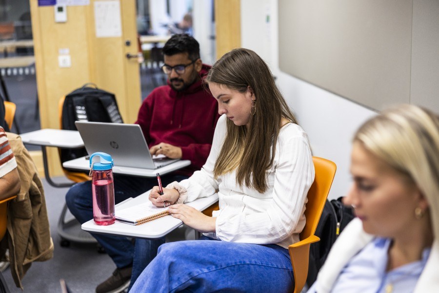 Kolme opiskelijaa istuvat luokassa ja opiskelevat itsenäisesti.