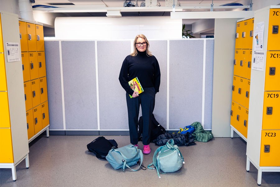 Johanna Asplund seisoo koulun käytävällä lokeroiden välissä ja katsoo kameraan.