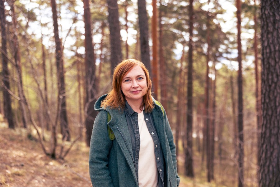 Helena Leino looks at the camera outside, with nature and trees in the background.