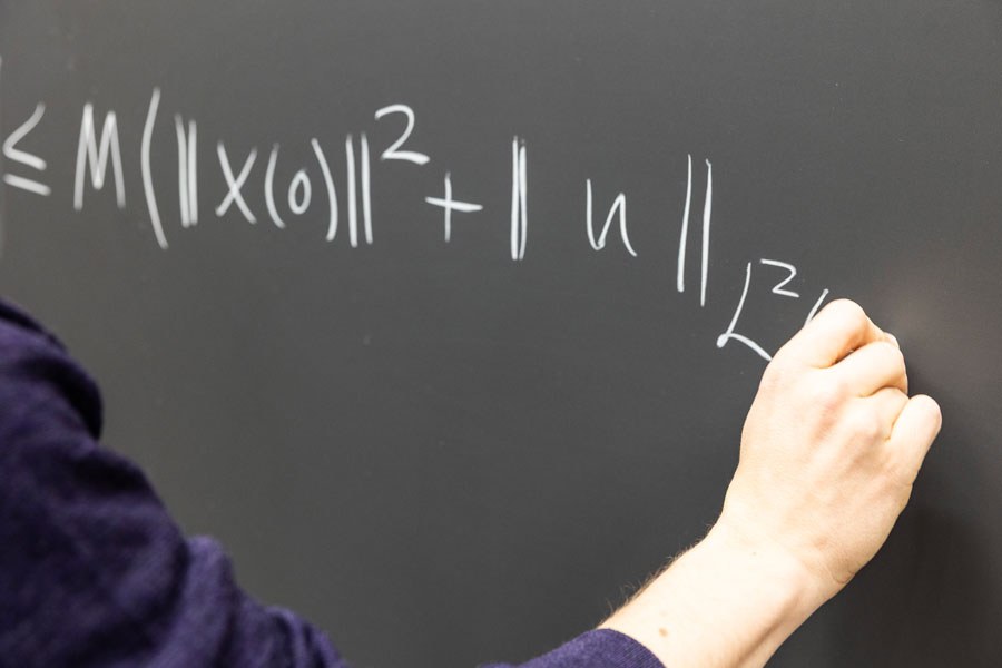 Professori Lassi Paunonen kirjoittaa liitutauluun matemaattista todistusta.