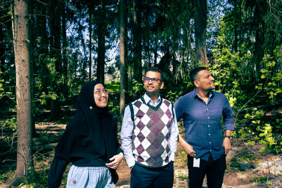 Three people, trees in the backround. 