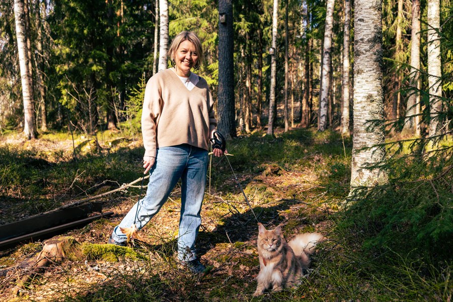 Professori Sanna Kumpulainen metsässä kissansa kanssa.