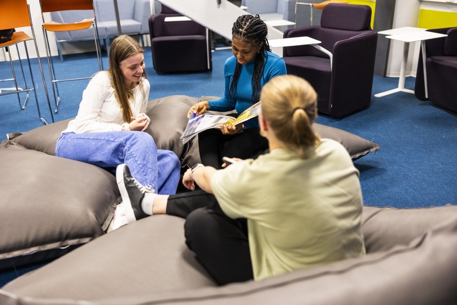 Opiskelijat keskustelemassa ja istumassa lattiatyynyjen päällä.