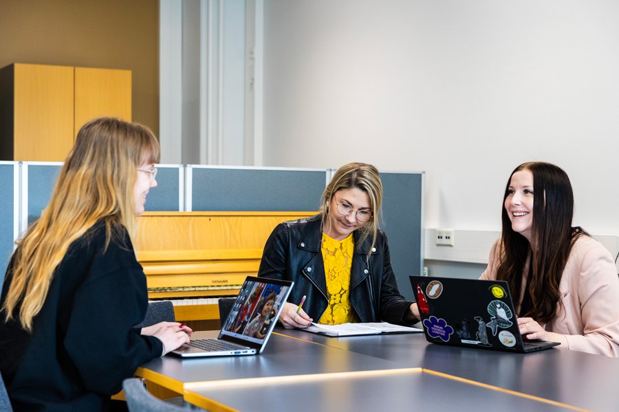 Kolme henkilöä työskentelee pöydän ääressä.