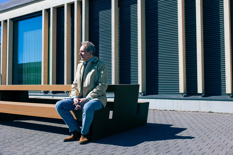 Klaus Ranta istuu penkillä ulkona ja katsoo horisonttiin, taustalla piharakennuksen seinä ja ikkunat..