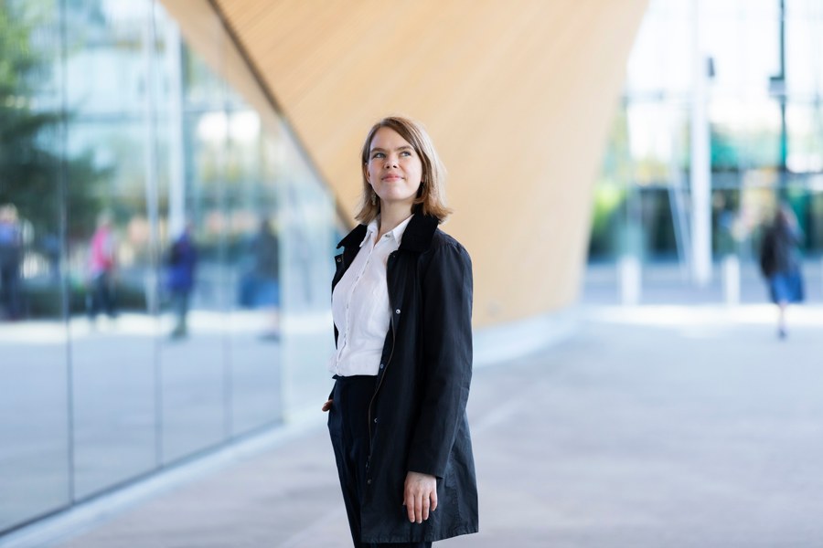 Riie Heikkilä in front of the glass of the building.