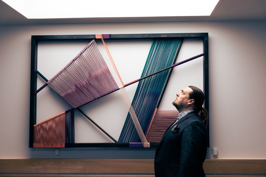 Tuukka Ahoniemi katsoo yläviistoon seinällä olevat taideteoksen äärellä.