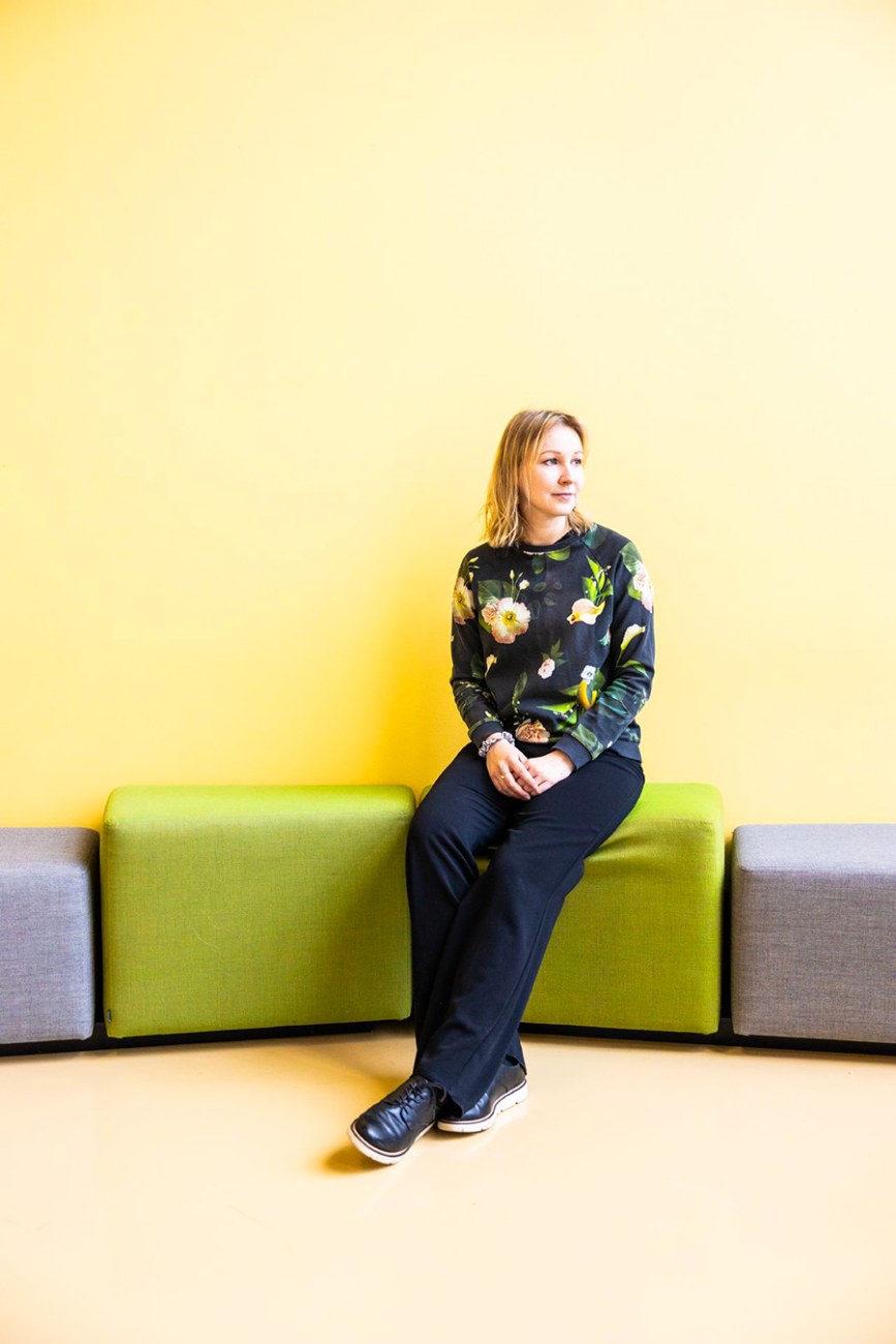 A person sitting on a lime green pouf, facing slightly to the side, away from the camera.