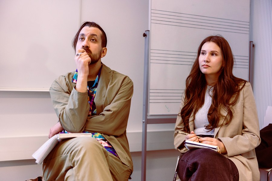 Aleksi Kivimaa and Maria Rossi listening intently in front of the class.
