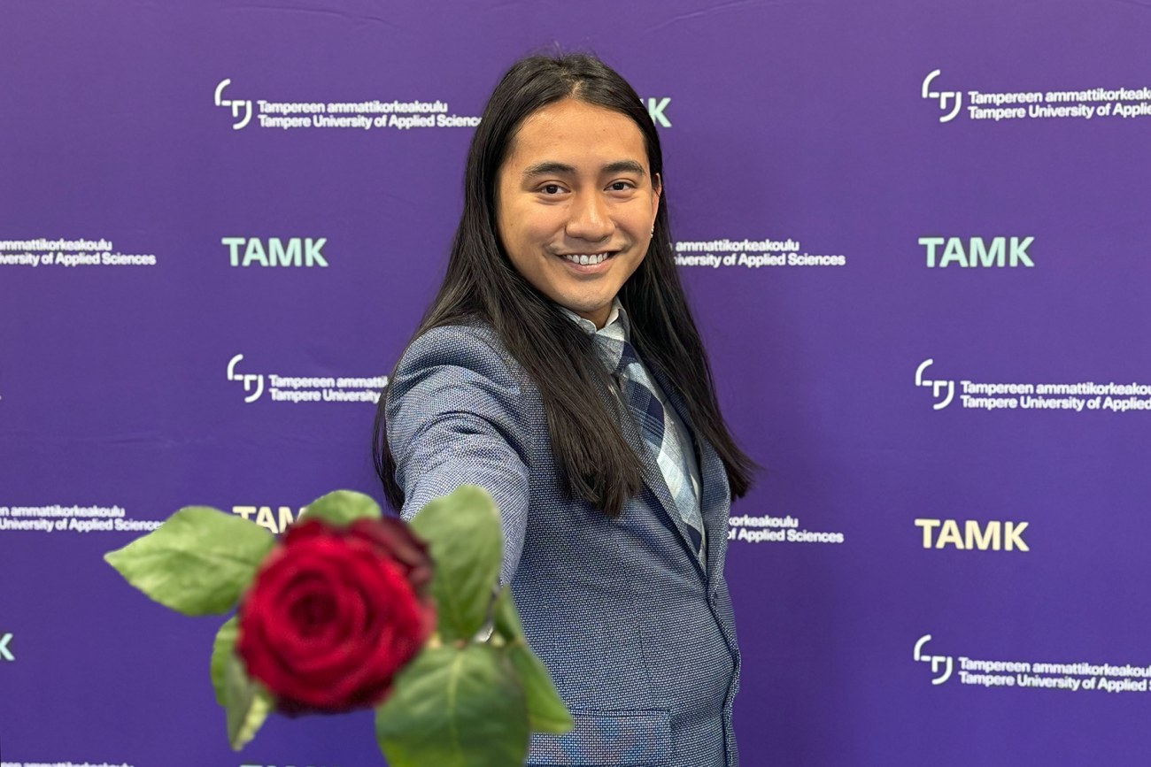 Kaipo van Kampen in front of the photo wall with a rose. 