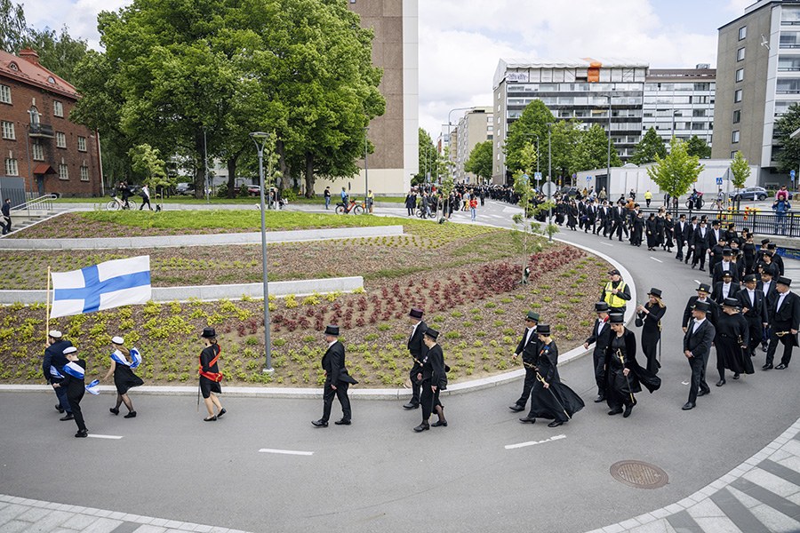 Tohtorit kulkevat jonossa Tampereen kadulla