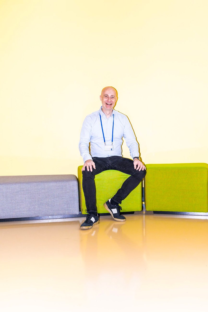 A person is sitting in a lime green pouf and smiling widely.