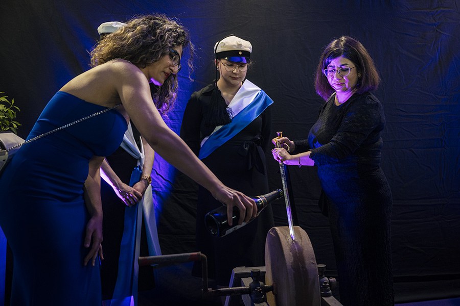 Kaksi henkilöä hioo tohtorinmiekkaa tahkolla