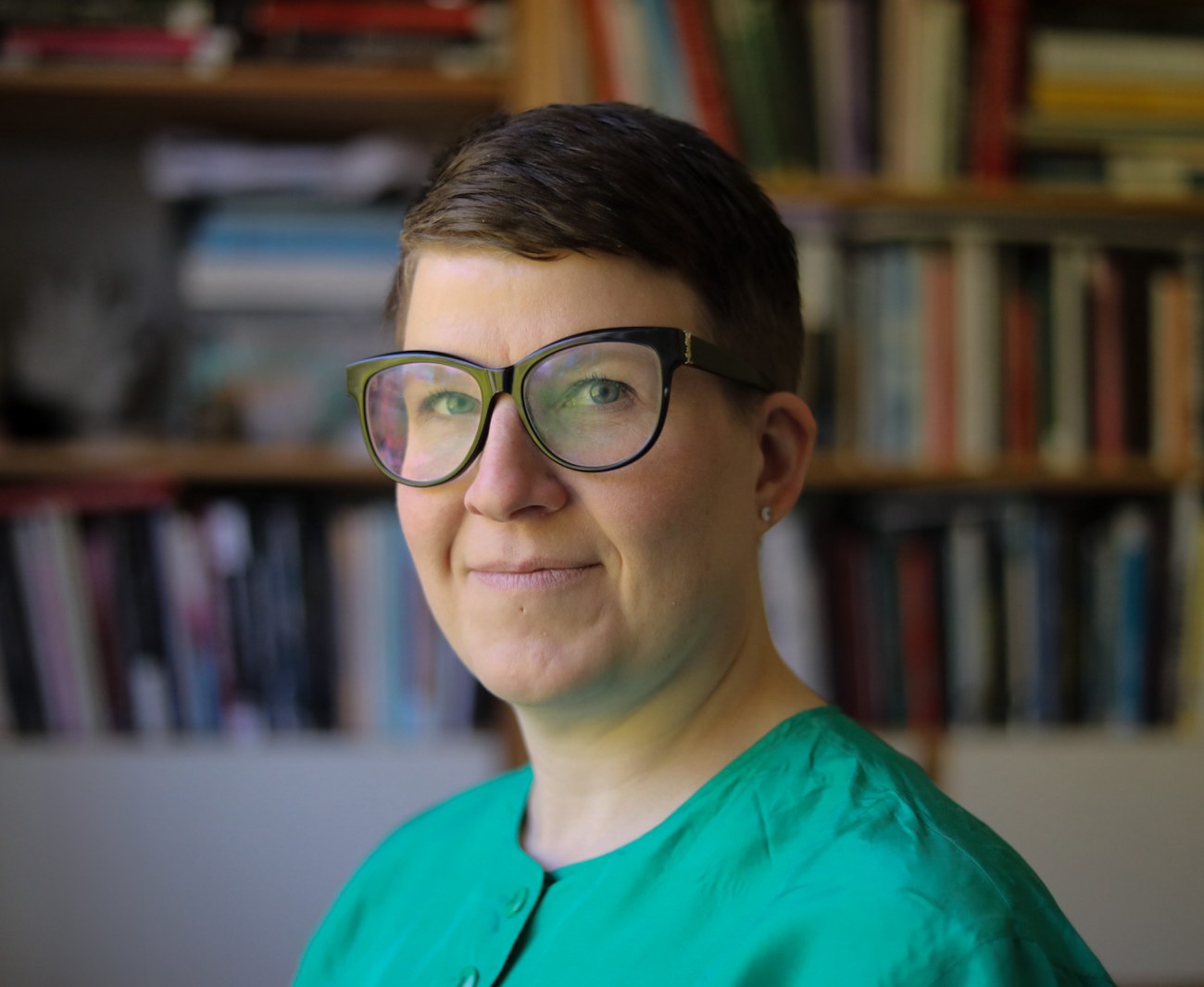 Lähikuva Niina Uusitalosta, taustalla kirjahylly.