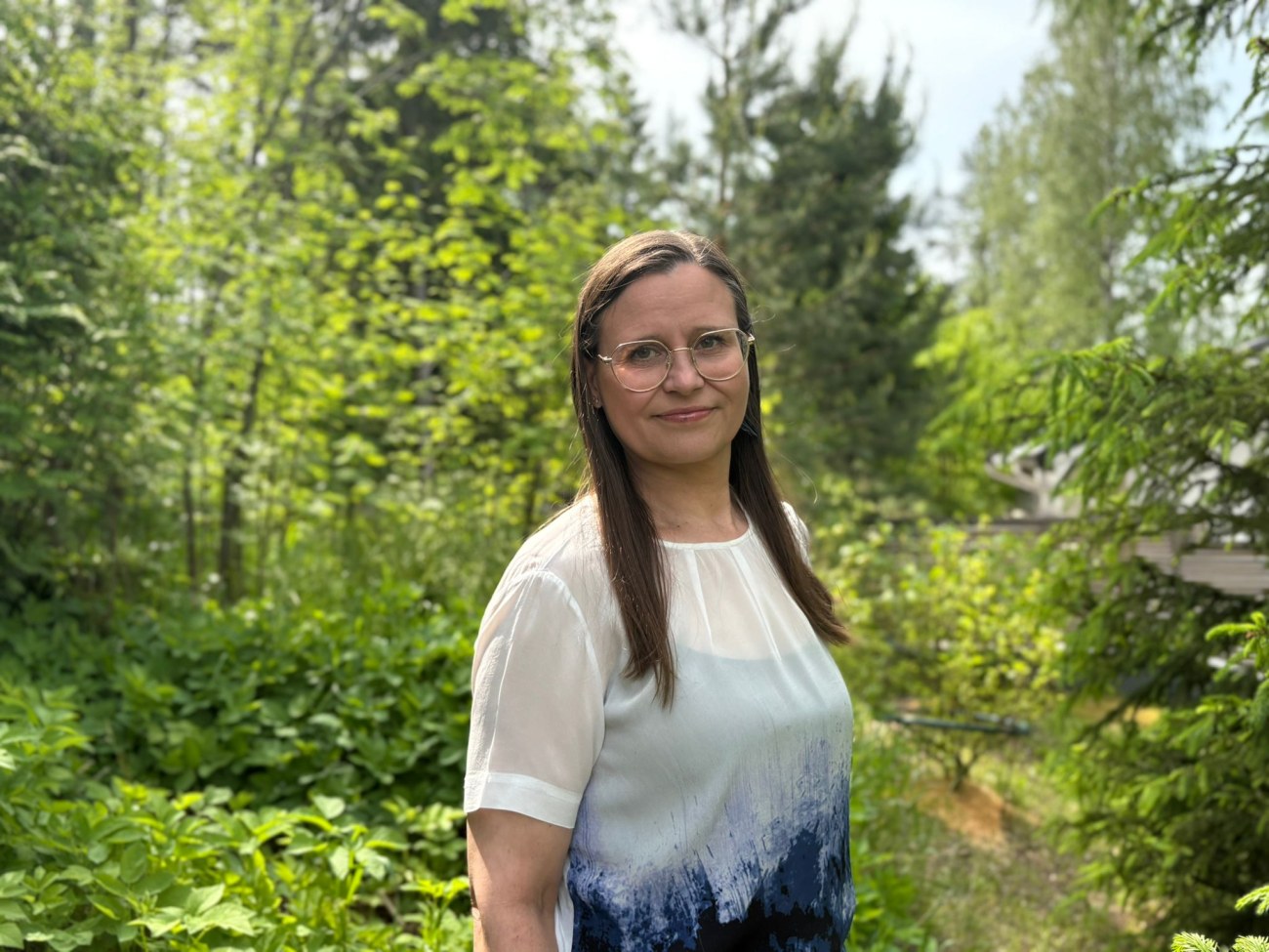 Pauliina Penttilä puolilähikuvassa, taustalla vihreä puutarha.