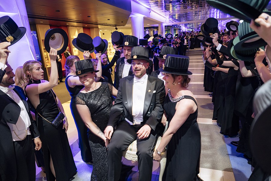 Tohtorit kantavat promoottoria tuolissa kunniakujan läpi