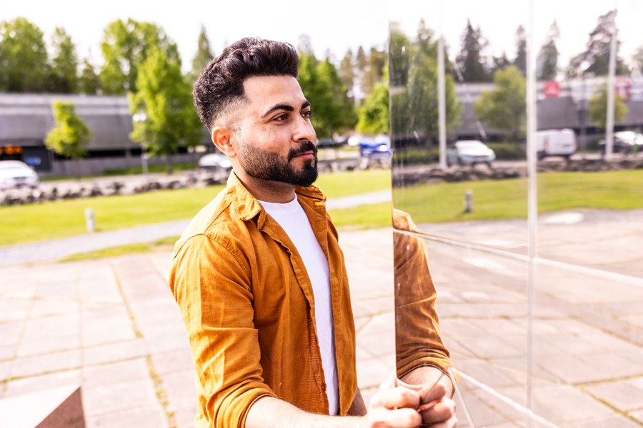 Ahtesham Rehman seisoo rakennuksen ulkopuolella peilaavan ikkunan edessä.