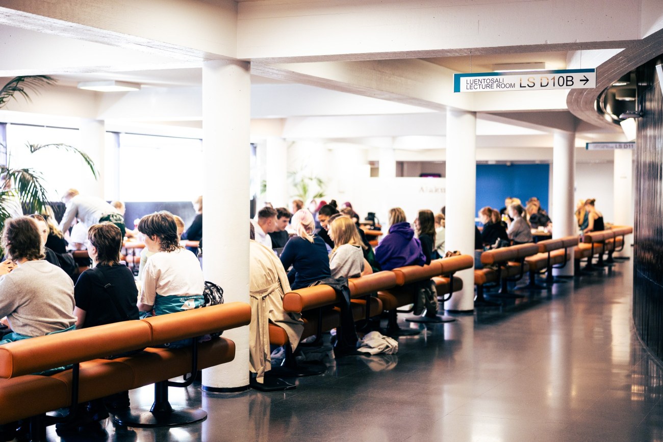 Opiskelijoita Tampereen yliopiston keskustakampuksen alakuppilassa, selkä kameraan päin.