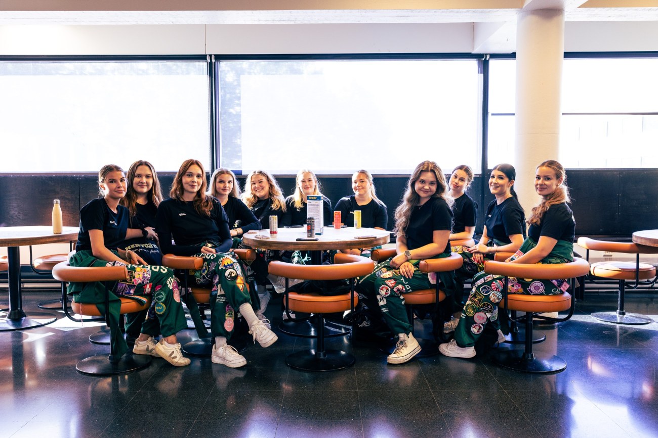 Joukko tuutoreita istuu kahvilassa ja katsoo kameraan.