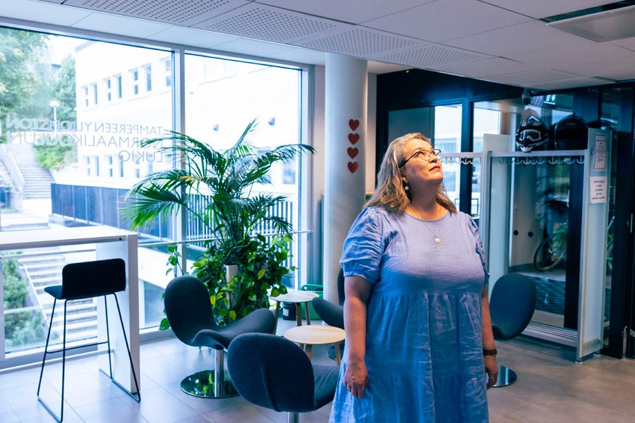 Aulikki Leisku-Johansson katsoo ylöspäin aulatiloissa Tampereen Norssin lukiossa..