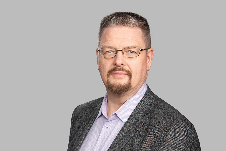 Pukuun pukeutunut mies katsoo kameraan. 