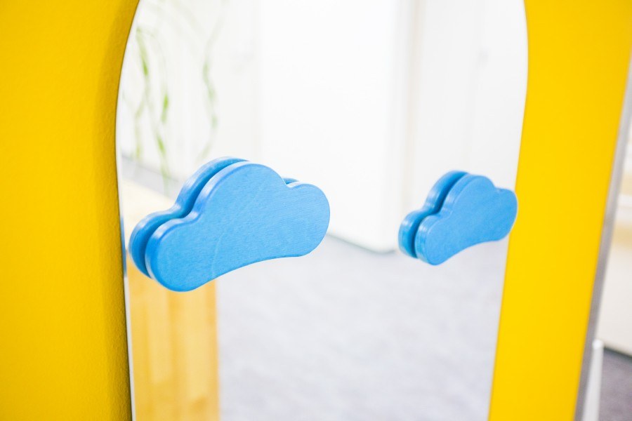 Kirkkaalla taustalla peili, jossa on kaksi pilvikuviota kiinnitetty.