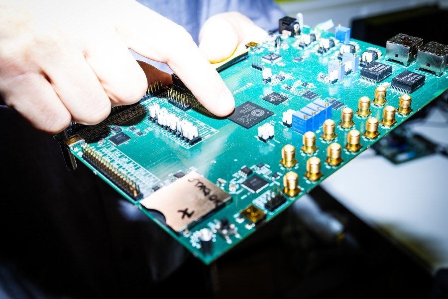 Professori Pekka Jääskeläinen osoittaa komponenttia, jossa on pieni vähävirtainen prosessori.