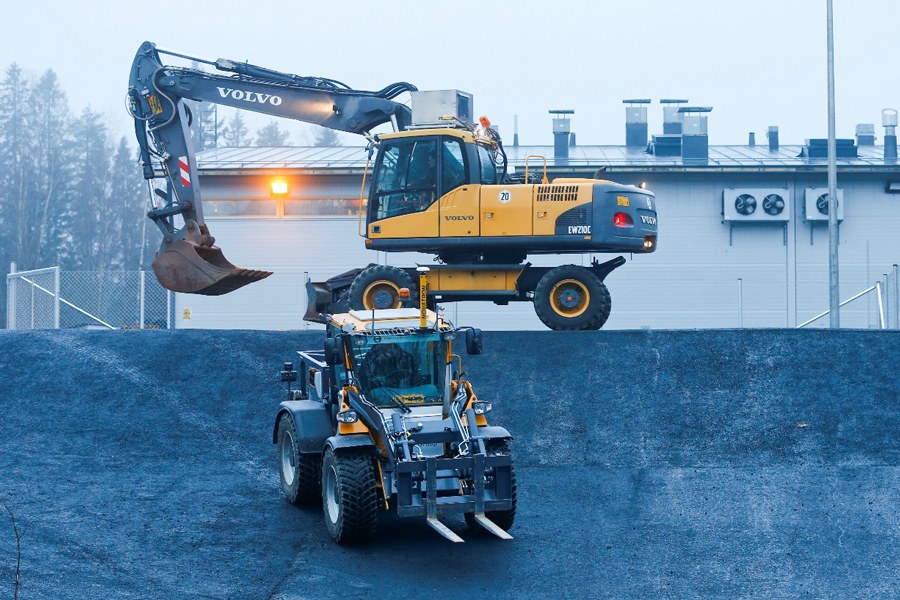 Kaivinkone ja pyöräkuormaaja ulkona varastohallin edessä.