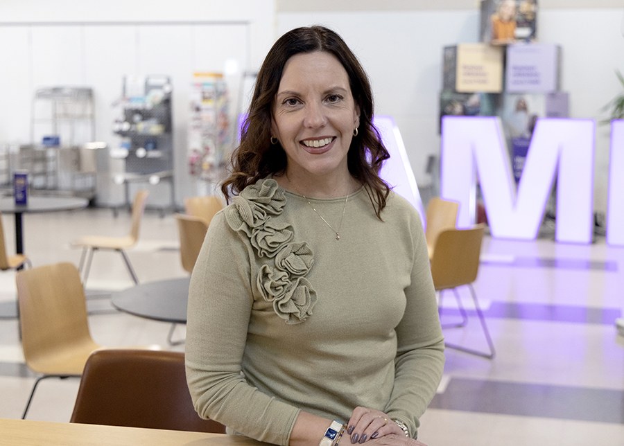 Nainen nojaa pöytään sisätiloissa.